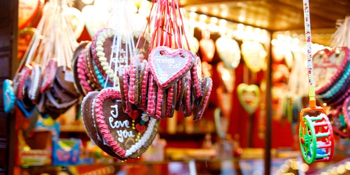 Heart-shaped gingerbread cookies hanging at a colorful market stall.